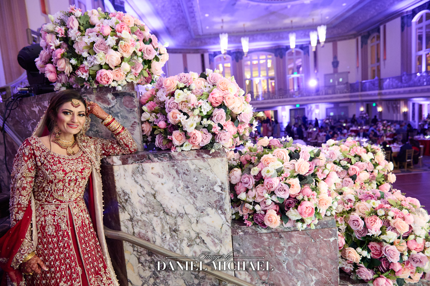 South Asian bride in traditional attire posing in front of lavish floral decorations at the Hilton Hall of Mirrors in Cincinnati